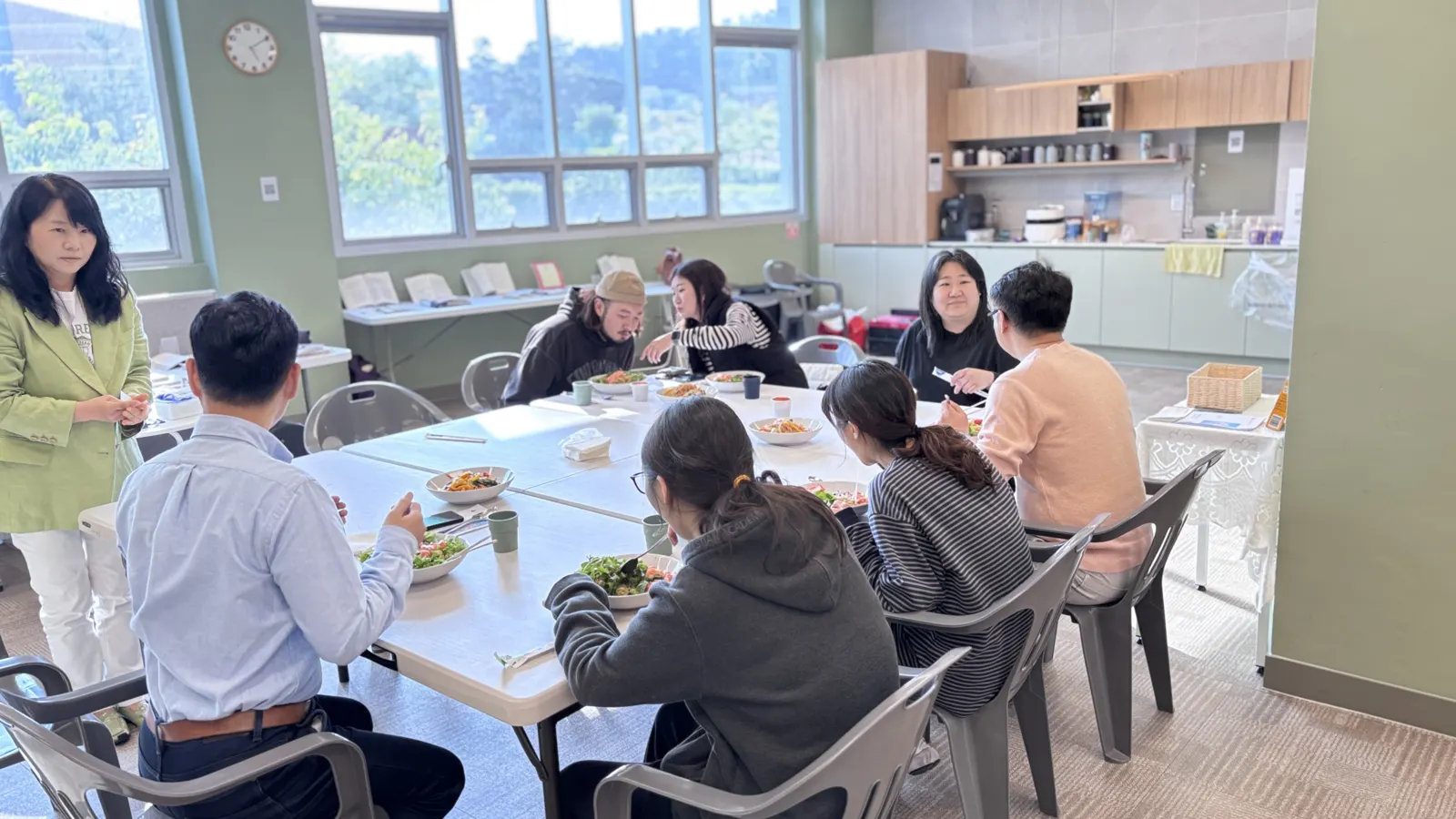 긴 식탁에 함께 앉아 식사하는 사람들